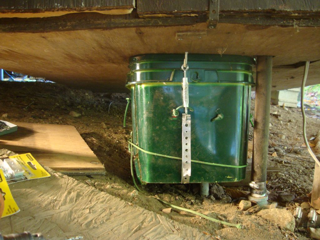 Work on the cathouse
This kitty-litter container, lined with high-R insulation, contains the lake valve. New this summer is the metal strap and turnbuckle. (This "cathouse" is mounted to the bottom of the "doghouse" that insulates most of the plumbing.)